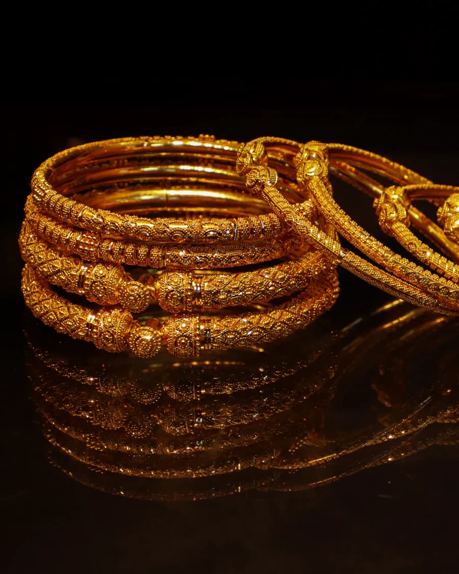 Ornate gold bangles with reflections on a dark glossy surface (illustrative photo)